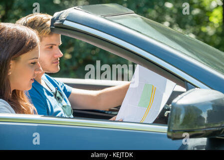 Seitenansicht einer jungen Frau auf der Suche auf Karte während der Mann Auto Stockfoto