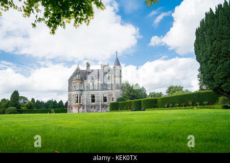 Große grüne Wiese und Gärten vor entfernten steinernen Burg unter blauem Himmel mit großen weißen Wolken. Stockfoto