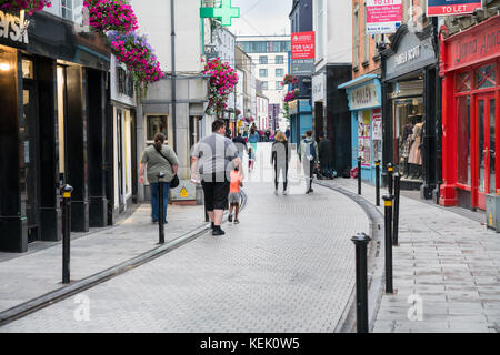 Wexford, Irland - 14 August, 2017; Familie wandern in der irischen Kleinstadt Gasse zwischen den Reihen von Shop- und traditionellen Geschäft Frontseiten. Stockfoto