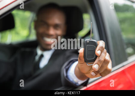 Glückliche junge afrikanische Unternehmer sitzen in einem Auto mit dem Schlüssel Stockfoto