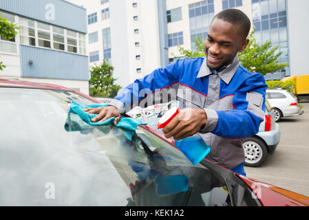 Junge afrikanische Arbeiter Auto Windschutzscheibe mit Tuch abwischen Stockfoto