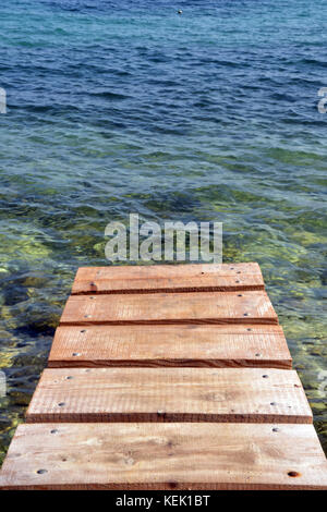 Eine wackelige, baufälligen baufälligen alten abgenutzten Holzsteg oder Pier am Mittelmeer Anlegestellen für Boote oder Schwimmen im klaren Wasser von einer Plattform aus Stockfoto