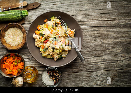 Risotto mit Hähnchen und Gemüse auf hölzernen Tisch serviert Stockfoto