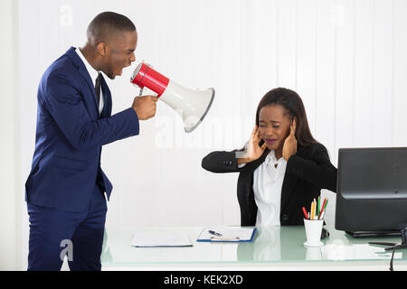 Boss schreien an junge geschäftsfrau über Lautsprecher im Büro Stockfoto