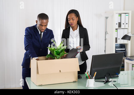 Zwei afrikanische amerikanische Geschäftsleute Verpackung Ordner in Karton am Arbeitsplatz Stockfoto