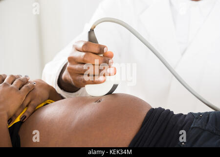 In der Nähe des Doctor's Hand bewegen Ultraschallaufnehmer an schwangeren Bauch Stockfoto