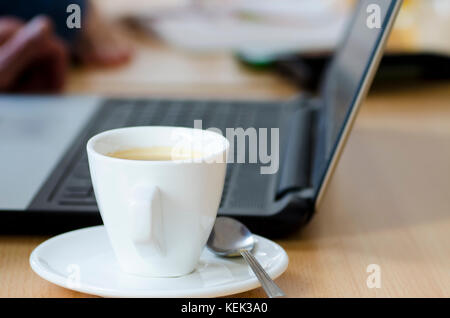 Laptop Foto mit Tasse Kaffee und Notizblock auf Holztisch auf Business break Treffen mit verschwommenen Hintergrund Stockfoto