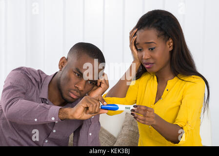 Unglückliche junge afrikanische Paar an der Schwangerschaft Test suchen Stockfoto