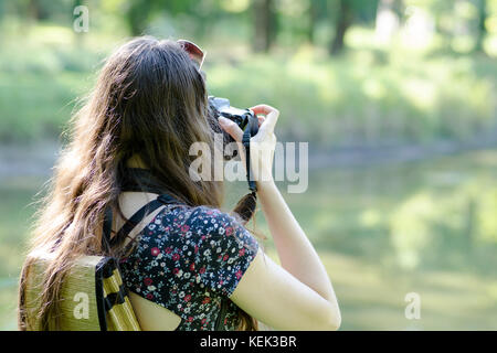 Eine Ansicht der Rückseite eine junge Frau mit Sonnenbrille und Rucksack natur Fotografieren mit einem unscharfen Hintergrund Stockfoto