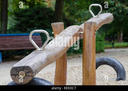 Bild Holz Holz schaukeln mit Edelstahl Griffe mit Regentropfen auf einem Spielplatz in einem herbstlichen regnerischen Tag Stockfoto