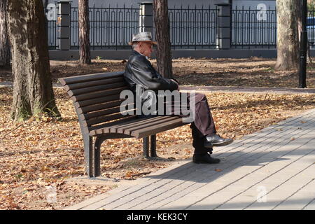 Einsame ältere Mann sitzt auf einer Parkbank Stockfoto