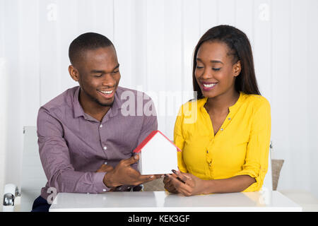 Junge glücklich Afrikanischen Paar hält ein Haus Modell zu Hause Stockfoto