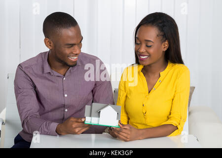 Junge glücklich Afrikanischen Paar hält ein Haus Modell zu Hause Stockfoto