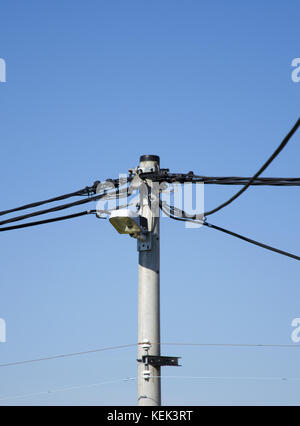 Ansicht einer Säule von Stromleitungen mit Telefonkabeln Und eine Straßenlampe unter einem blauen klaren Himmel an Ein sonniger Tag Stockfoto