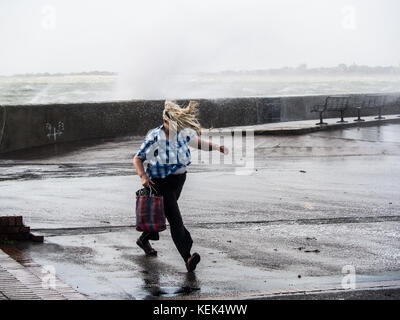 Southsea, Portsmouth, Großbritannien. Oktober 2017. Wetter in Großbritannien. Eine Dame hat Schwierigkeiten, auf der Southsea Promenade zu spazieren, während Wellen über die Meeresmauer von Southsea brechen, während Sturm Brian bei Flut die Südküste Großbritanniens trifft. Quelle: simon evans/Alamy Live News Stockfoto