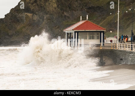 Aberystwyth, Wales, UK. 22. Oktober 2017. Am Tag nach aberystwyth nahm ein Zerschlagen von Sturm Brian. Ein Mann flüchtet sich in der promenade Tierheim als eine Welle gegen die Promenade Wand stürzt. Credit: Alan Hale/alamy leben Nachrichten Stockfoto