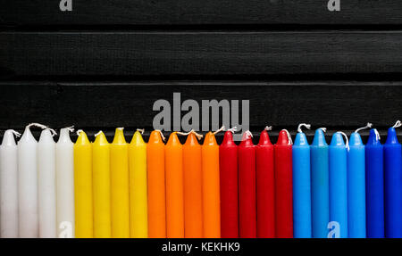 Viele bunte Kerzen in einer einzelnen Zeile und Line, schwarzer Hintergrund, Kerzen der pulsierenden Weiß. Gelb, Orange, Rot und Blau, in einem Regenbogen Farbverlauf Stockfoto