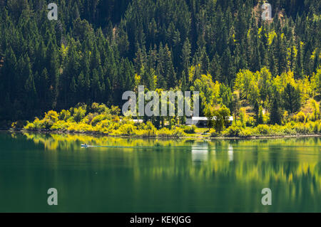 Ein Fischer auf dem Boot an einem kleinen See Seite home entlang der noch Wasser der Gros Ventre untere See in Wyoming, der sonnendurchfluteten reflektierende früh ein Stockfoto
