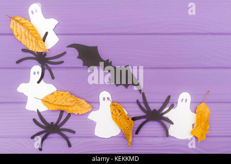 Die Fledermaus, Gespenster, Spinnen und anderes Papier Silhouetten mit Blätter im Herbst Halloween Ecke Rahmen auf einem violetten Holztisch. Halloween celebrat Stockfoto