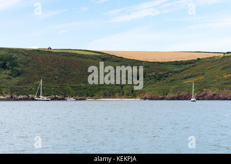 Yachten in watwick Bucht mit einem Traktor Schneiden von Gras auf die Felder oben verankert Stockfoto