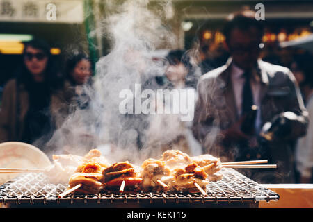 Gegrillten Meeresfrüchten Jakobsmuscheln und Meer ​​urchin Eier Spieß mit Rauch, japanisch Essen in Tsukiji Fischmarkt, Japan. selektive Fokus und Film Stil. Stockfoto