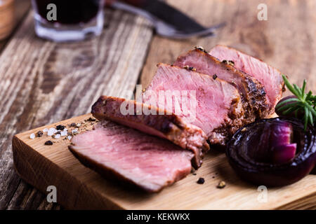 Leckeres Rindfleisch Filet Mignon serviert auf Holz Schneidebrett mit gerösteten Zwiebeln und Rosmarin Stockfoto