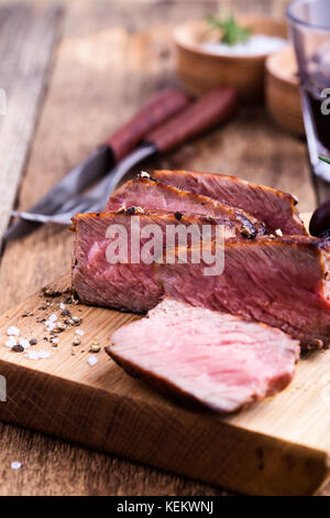 Leckeres Rindfleisch Filet Mignon serviert auf Holz Schneidebrett mit gerösteten Zwiebeln und Rosmarin Stockfoto