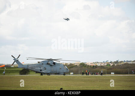 Fleet Air Arm Agusta Westland Merlin HM 1 Hubschrauber, RNAS Culdrose Sea King fliegen im Hintergrund Stockfoto