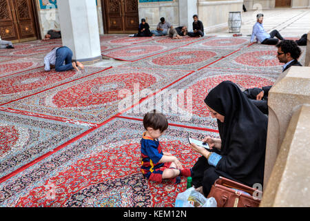 Shiraz, Iran - 19. April 2017: Iranische muslimische Frau, in einem tschador mit Ihrem Kind gekleidet, ein Junge von fünf Jahre alt, liegt im Innenhof des Stockfoto