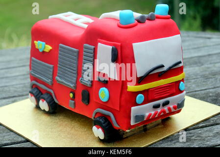 Child's hausgemachte red fire engine Geburtstag Kuchen auf einen Tisch draußen Stockfoto