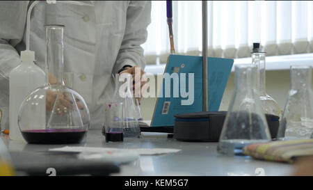 Labortechniker macht Experimente im Labor. Männlicher medizinischer oder wissenschaftlicher Laborforscher führt Tests mit blauer Flüssigkeit durch. Wissenschaftler, die mit Kolben im Labor arbeiten Stockfoto