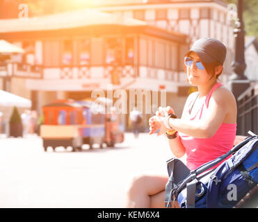 Foto der Frau in der Sonnenbrille auf die Uhr auf unscharfen Stadt Hintergrund mit Sommer Tag suchen Stockfoto