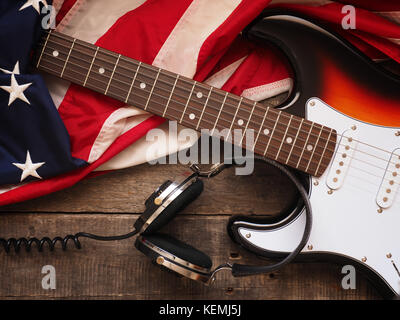 Alte gebrauchte Rock Gitarre mit Kopfhörern und die amerikanische Flagge auf rustikalen, mit Holz, Musik oder Sound Konzept Hintergrund Stockfoto