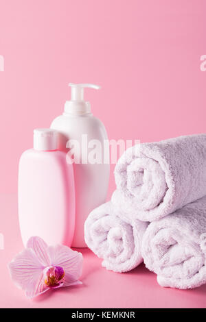 Handtücher mit Duschgel und Bodylotion auf rosa Hintergrund Stockfoto