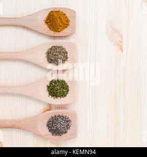 Essen kochen Zutaten. getrocknete Gewürze Currypulver, schwarzer Pfeffer, Pulver, Oregano und Thymian in hölzernen Löffel auf rustikalen Holzmöbeln Hintergrund. Stockfoto