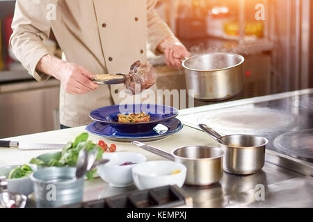 Koch Hände halten gekochte Lammkeule. männliche Chef auf die lammkeule in die Platte mit garnieren. Vorbereitung der leckeres Gericht auf europäischer Restaurant kit Stockfoto