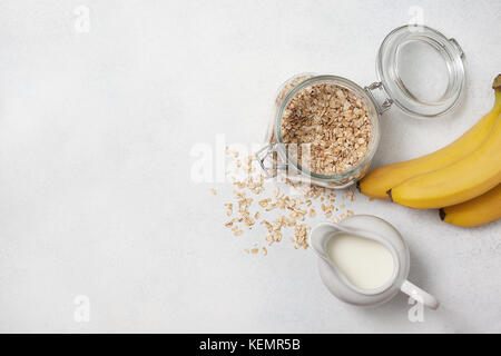 Zutaten für das Frühstück: Milch, Haferflocken, Bananen auf einem hellen Hintergrund. Ansicht von oben, Kopie Raum Stockfoto