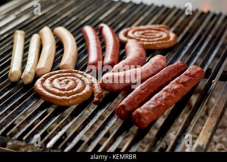 Sortiment Würstchen grillen auf Metallgitter. verschiedene köstliche gegrillte Fleisch über die Kohlen auf einem Grill. Stockfoto