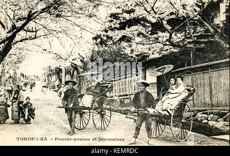 Japan, Yokohama. Jahrgang, ca. 1900, schwarze und weiße Postkarte von Rikschas in Street, mit Frauen in Kimonos sitzen in der Rikscha. Stockfoto
