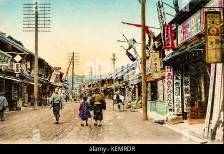 Japan, Yokohama. Jahrgang, ca. 1900, handkoloriert Postkarte des Yoshidamachi Dori Straße. Zweistöckige Gebäude und Telegrafenmasten. Stockfoto