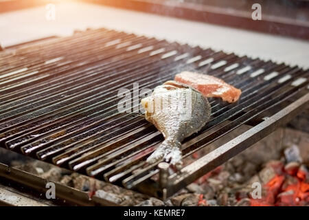 Dorado Fisch grillen am Grill zubereitet. roher Fisch mit Gewürzen und Zitrone auf den Grill. Stockfoto