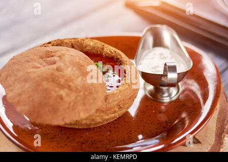 Ukrainische Rote Bete und Tomatensuppe. Suppe mit roten Rüben und Rindfleisch in Brot pot. Traditionelle ukrainische Gericht. Stockfoto