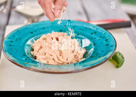 Koch Kochen Pasta Crema di Pollo. Küchenchef Hand servieren Fettuccine Pasta mit Käse essen vorbereiten und das kulinarische Konzept. Stockfoto