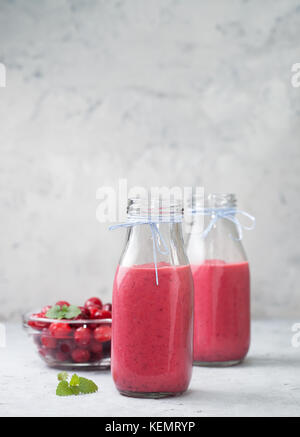 Smoothies Preiselbeeren im Glas Flaschen, frische Cranberries in einer Schüssel auf einem grauen konkreten Hintergrund Stockfoto