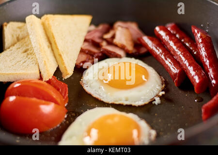 Englisches Frühstück in Pan. englisches Frühstück in der Pfanne mit Spiegelei, Würstchen, Speck, Tomaten und Toast. Traditionelles, englisches Frühstück. Stockfoto