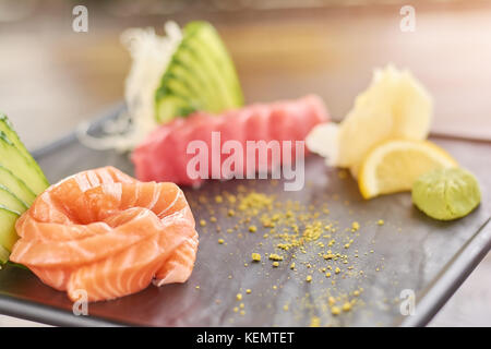 Roher Lachs auf schwarze Platte geschnitten. Lachs und Thunfisch Sashimi. Leckeres Essen der japanischen Kultur. Stockfoto