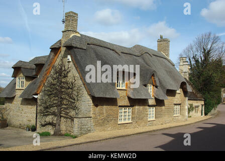 Freistehendes Haus, mit Kaminen und einem Strohdach, in der Ortschaft Duddington, Northamptonshire, Großbritannien Stockfoto