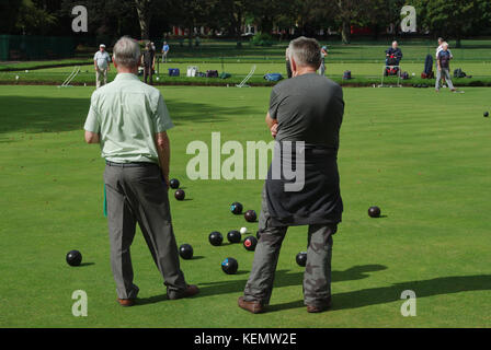 Eine Boccia Spiel im Gange in Abington Park, Northampton; zwei männliche Spieler, Rücken zur Kamera, beobachten. Stockfoto