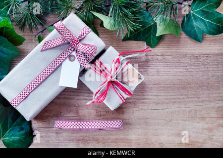 Grenze von Efeu Blätter und Zweige Tannenbaum, mit rustikalen Weihnachtsgeschenke auf abstrakte Holz- Hintergrund. nach oben anzeigen und Platz für Text. Stockfoto