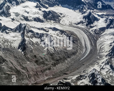 Riesige hohe Berge, Gletscher: der moräne Eis Zunge Kurven unter den schneebedeckten Berggipfeln und der Bogen hinab in das Tal von Ladakh, Tibet, Stockfoto